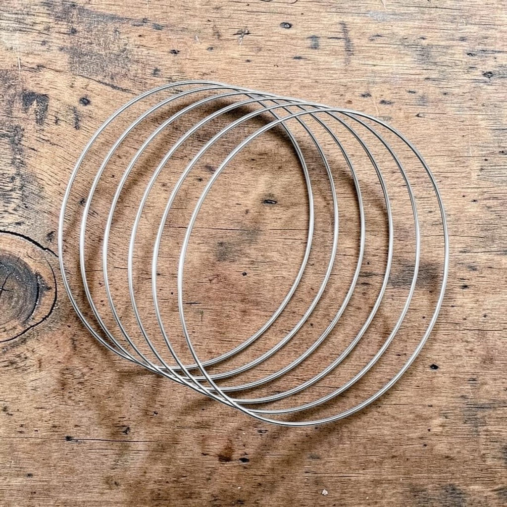 Saaika Crafts silver steel metal rings for macrame, dream catchers, and DIY craft projects on a wooden surface.